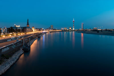 Illuminated bridge over river by city against sky at night