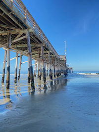 Pier on beach against blue sky