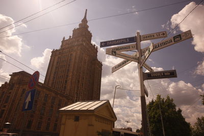 Low angle view of road sign boards and latvian academy of sciences against sky