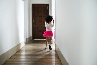 Rear view of girl walking on floor at home