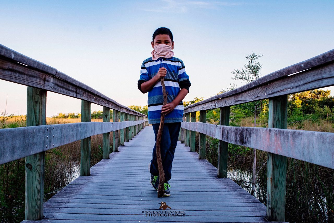 outdoors, bridge - man made structure, one person, technology, footbridge, full length, railing, connection, summer, nature, sky, people, one man only, day, water, digital native, adult, adults only