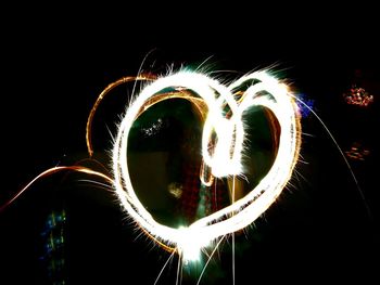 Blurred motion of illuminated ferris wheel against sky at night