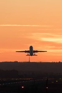 Airplane flying against orange sky