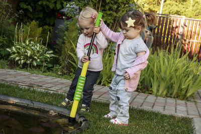 Two girls pumping water with children's pumps from a small pond.