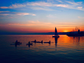 Silhouette sailboats in sea against sky during sunset