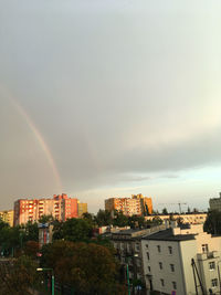 Rainbow over buildings in city against sky