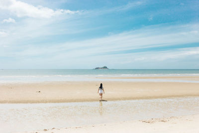 Man walking on beach against sky