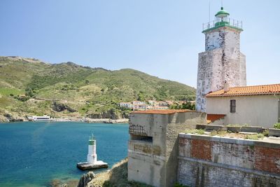 Lighthouse by buildings against sky