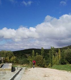 Rear view of man walking on road against sky