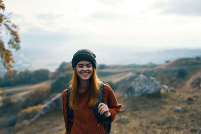 Portrait of smiling young woman standing against sky