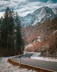 Road amidst snowcapped mountains against sky