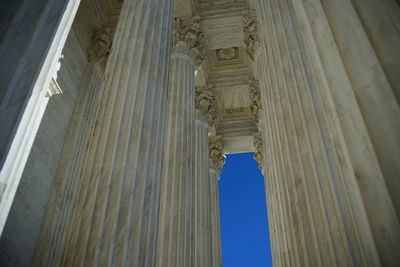 Low angle view of columns of the supreme court building on blue sky