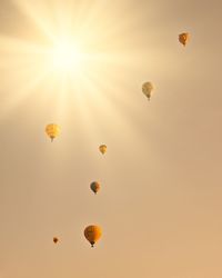 Low angle view of hot air balloons flying against sky during sunset