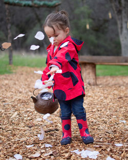 Girl throwing paper while standing at park during autumn