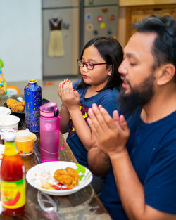 Father and daughter praying before eating food at home