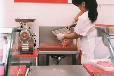 Rear view of butcher slicing meat in shop