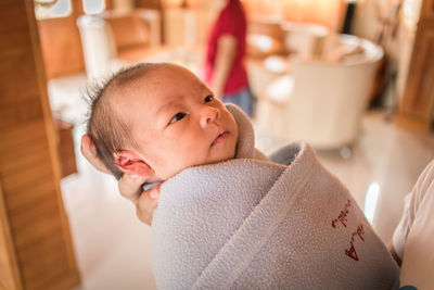 Cropped image of mother holding newborn baby at home