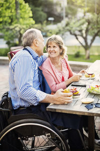 Happy mature couple looking at each other while having food in yard