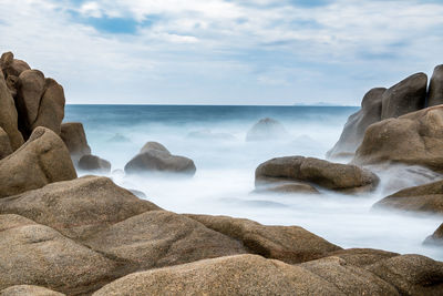 Scenic view of rocks in sea against sky