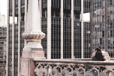 Rear view of woman sitting against building