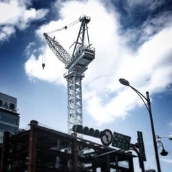 Low angle view of crane against sky in city