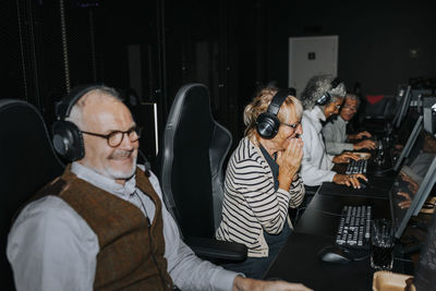 Multiracial male and female friends playing game on computers in gaming center