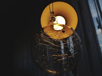 Close-up of illuminated lamp hanging against wall