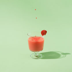 Summer strawberry juice with falling drops isolated on a green background. minimal abstract concept.