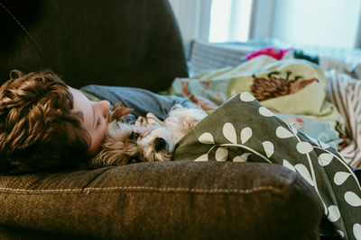 Boy and dog sleeping on sofa at home