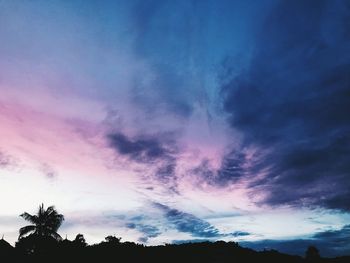 Low angle view of silhouette trees against dramatic sky