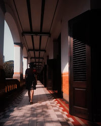 Rear view of woman walking on footpath amidst buildings