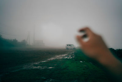 Person photographing against sky during foggy weather