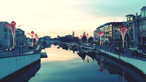 Boats moored in canal against sky during sunset