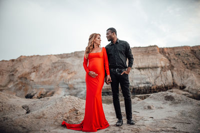 Rear view of couple standing on land against sky