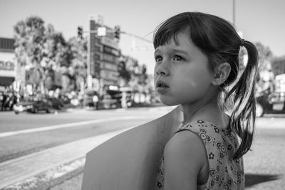 Close-up of girl holding placard while standing on footpath