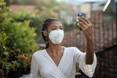 Young black woman in face mask using a smartphone