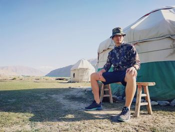 Young man sitting on sunglasses against sky