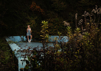 Woman standing by plants in forest