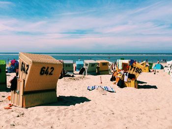 Hooded chairs on beach against sky