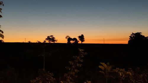 Silhouette trees on landscape against sky during sunset