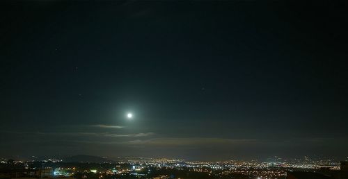 Illuminated cityscape against sky at night