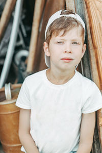 Portrait of a tired boy sits leaning against the barn door with green eyes. 