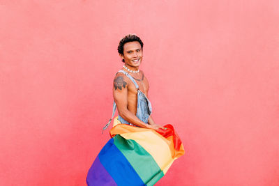 Side view of gay man against pink wall