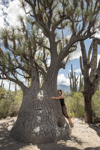 Side view of man standing on tree trunk