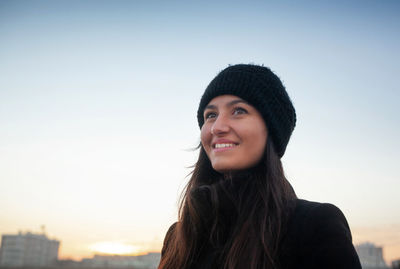 Portrait of smiling young woman against clear sky