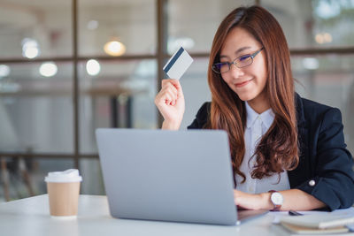 Smiling businesswoman using laptop while holding credit card