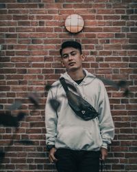 Young man standing against brick wall