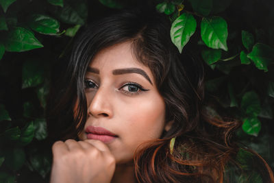 Portrait of young woman with green leaves