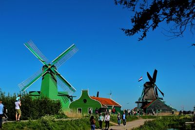 Traditional windmill on field against clear blue sky