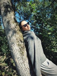 Midsection of woman on tree trunk